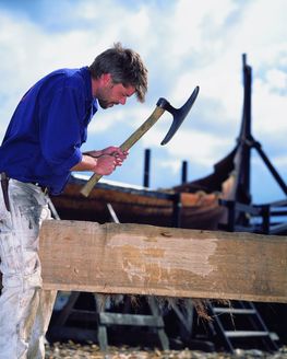 Vikingeskibsmuseets bådebyggere har bygget rekonstruktioner af samtlige Skuldelevskibe, Her tilhugges en planke til Skuldelev 2. 