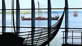 [Translate to english:] De originale vikingeskibe præsenteres smukt med udsigt til Roskilde Fjord
