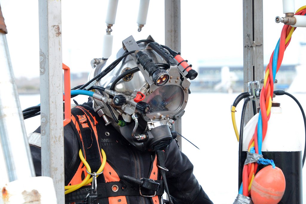 Marinarkæologerne arbejder med tungt udstyr. Hjelmen sørger for at de kan kommunikere med udgravningslederen, og kameraet optager alt de fortager sig på bunden.