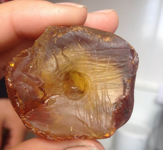 The unfinished amber amulet was fashioned from a lump of amber the size of a chicken egg. It has been worked and has clear hollow in the middle, where the craftsman began boring a hole, which most likely was intended to go the whole way through the amulet