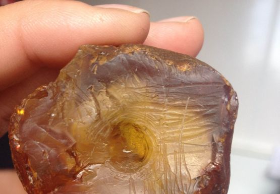 The unfinished amber amulet was fashioned from a lump of amber the size of a chicken egg. It has been worked and has clear hollow in the middle, where the craftsman began boring a hole, which most likely was intended to go the whole way through the amulet