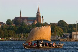 Sejlads på Roskilde Fjord med Roskilde Domkirke i baggrunden og de gyldne aftensolstråler på det udslåede sejl