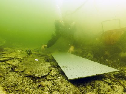 Marinarkæologen gør klar til at placere en skibsdel på den 'båre', der skal sikre at skibsdelen kommer uskadt frem til Vikingeskibsmuseet, hvor den skal analyseres og 3D-opmåles. Marinarkæologen gør klar til at placere en skibsdel på den 'båre', der skal sikre at skibsdelen kommer uskadt frem til Vikingeskibsmuseet, hvor den skal analyseres og 3D-opmåles.