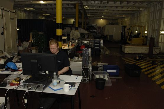 På en computer opstillet på mellemdækket er Anders i færd med at registrere de optagne genstande i databasen. Foto: Morten Johansen, Vikingeskibsmuseet.