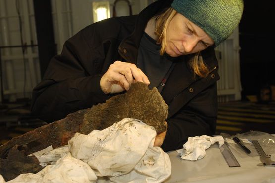 I øverste lastrum, kaldet ”mellemdækket,” er Athena i gang med at fjerne tangrester og begroning fra kobberkarret. Foto: Morten Johansen, Vikingeskibsmuseet.