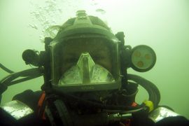 Marinarkæolog og erhvervsdykker Klara Fiedler iført den avancerede dykkermaske med indbygget mikrofon og øretelefoner, så dykkeren kan tale med dykkerlederen på overfladen. Desuden er masken er udstyret med videokamera og lys som begge betjenes fra o