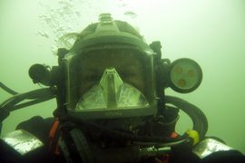 Marinarkæolog og erhvervsdykker Klara Fiedler iført den avancerede dykkermaske med indbygget mikrofon og øretelefoner, så dykkeren kan tale med dykkerlederen på overfladen. Desuden er masken er udstyret med videokamera og lys som begge betjenes fra o Marinarkæolog og erhvervsdykker Klara Fiedler iført den avancerede dykkermaske med indbygget mikrofon og øretelefoner, så dykkeren kan tale med dykkerlederen på overfladen. Desuden er masken er udstyret med videokamera og lys som begge betjenes fra o