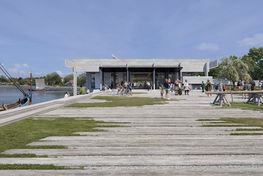 Visualisering Nyt Vikingeskibsmuseum. Hallen, eksteriør. En visualisering af den eksisterende Vikingeskibshal efter en transformation, hvor der skabes en ny offentlige plads vest for Vikingeskibshallen. Pladsen spiller sammen med den transformerede Vikingeskibshal, som åbner sig mod pladsen og tilbyder god visuel kontakt og en direkte adgang mellem pladsen og Vikingeskibshallens indre. Copyright: KVANT-1 og Lundgaard & Tranberg Arkitekter