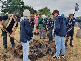 Spejderne hjælper kulsvigeren med at lave kul, så der kan smedes jernnagler til spejdernes båd.