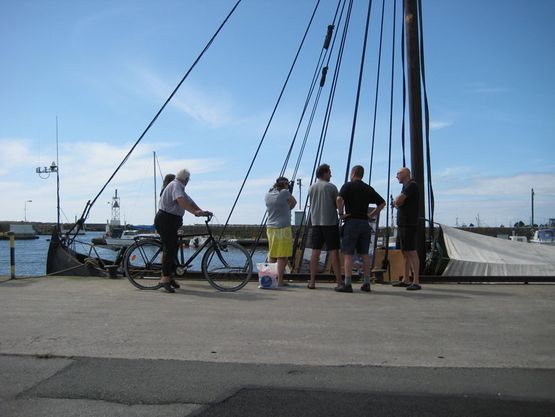 Folk flokkes på kajen i Nogersund, for at se det flotte gamle skib der er kommet ind. Mangt en ældre herre på cykel har været forbi.
