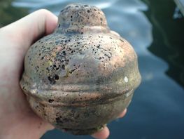 The shipwreck shows traces of a very violent fire. Among other things, archaeologists have found pieces of bronze cannons. The photo shows a so-called 'grape', the back end of a bronze cannon. The many holes in the bronze surface are clear signs of high heat. Photo: Morten Johansen / Viking Ship Museum