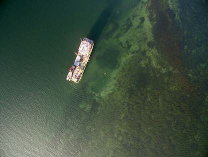 Droneoptagelse. Ortofoto af FØNIKS SUPPLY og arbejdsområdet. Udgravningen er den mørke plet midt i billedet nedenfor den dobbelte røde bøje. Det andet mørke område ovenfor dette er et af de gamle prøvehuller udgravet med maskine fra gravefartøjet