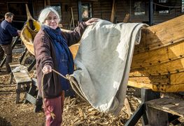 The Viking Ship Museum builds a new reconstruction of a Skuldelev ship. Weaver with handwoven sail.