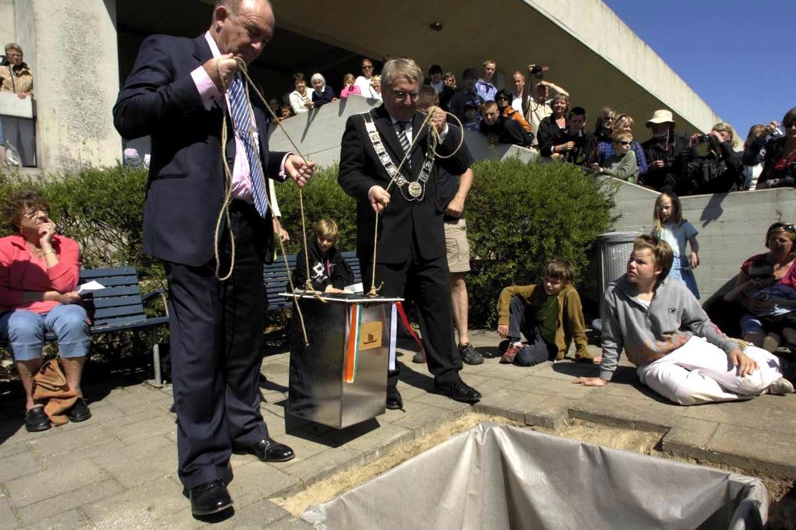 Den irske ambassadør Joe Hayes og Roskildes borgmester Poul Lindor Nielsen løfter ved fælles hjælp Tidskapslen på plads. Foto: Werner Karrasch