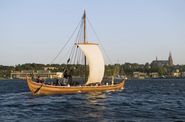 Helge Ask, en rekonstruktion af Skuldelev 5, for sejl på Roskilde Fjord med Vikingeskibshallen, Museumsøen og Domkirken i baggrunden.